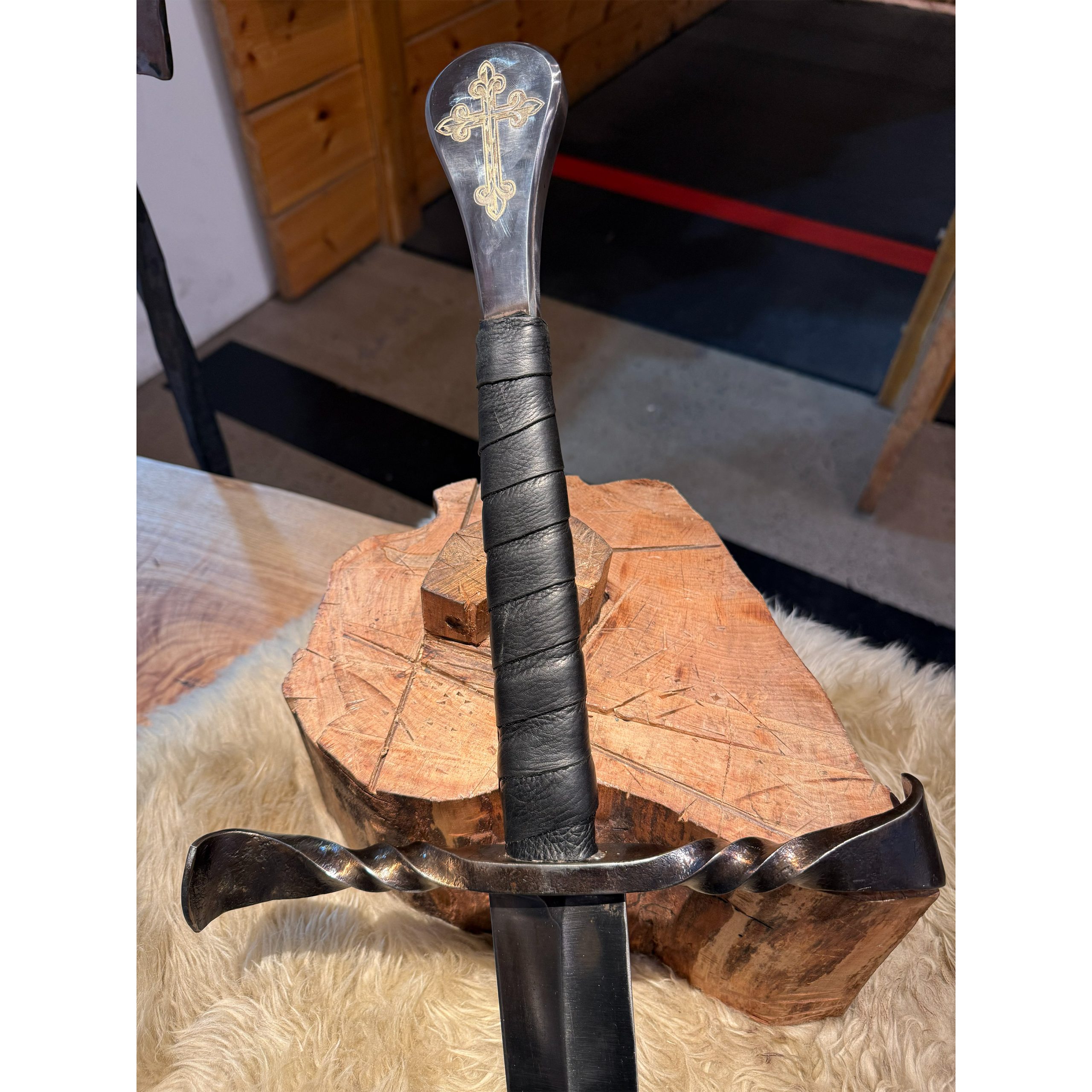 close up on twisted crossguard and pommel with laser engraving of a cross